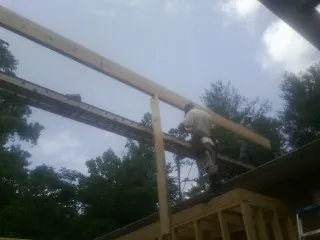 Carpenter setting a ridge beam over a new addition frame — Ice Dam Removal by Roofing Brothers in Neola