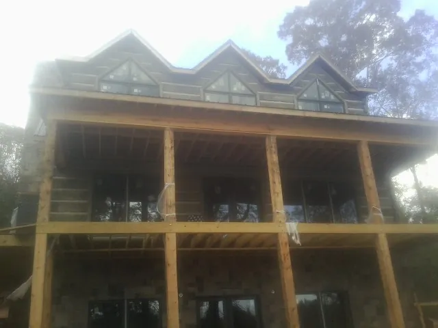 Dormers and porch framing on a large log home under construction — Roof Coating work by our crew in Neola
